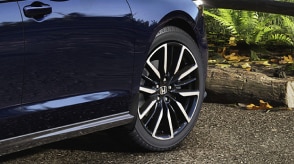 Closeup of wheel on a blue Accord outdoors.