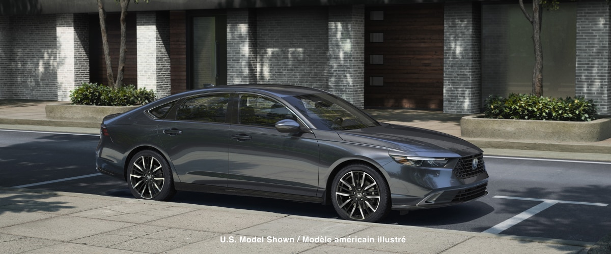 3/4 side view of grey Accord parked curbside on a sunny day in an upscale urban neighbourhood, with wooden townhome garage doors behind it.