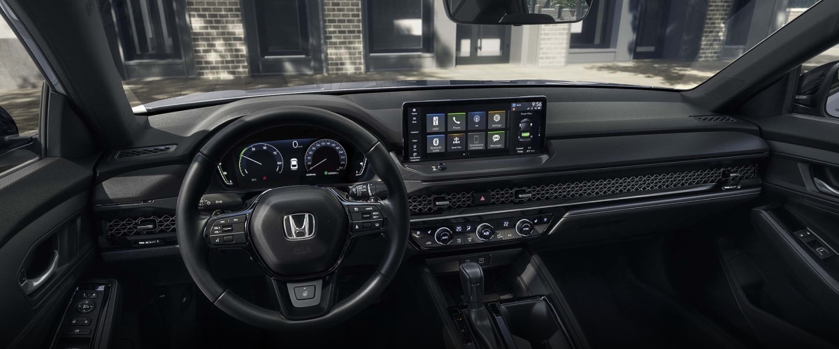 Panoramic wide view of steering wheel and dashboard. Trendy condo building can be seen through the windshield.