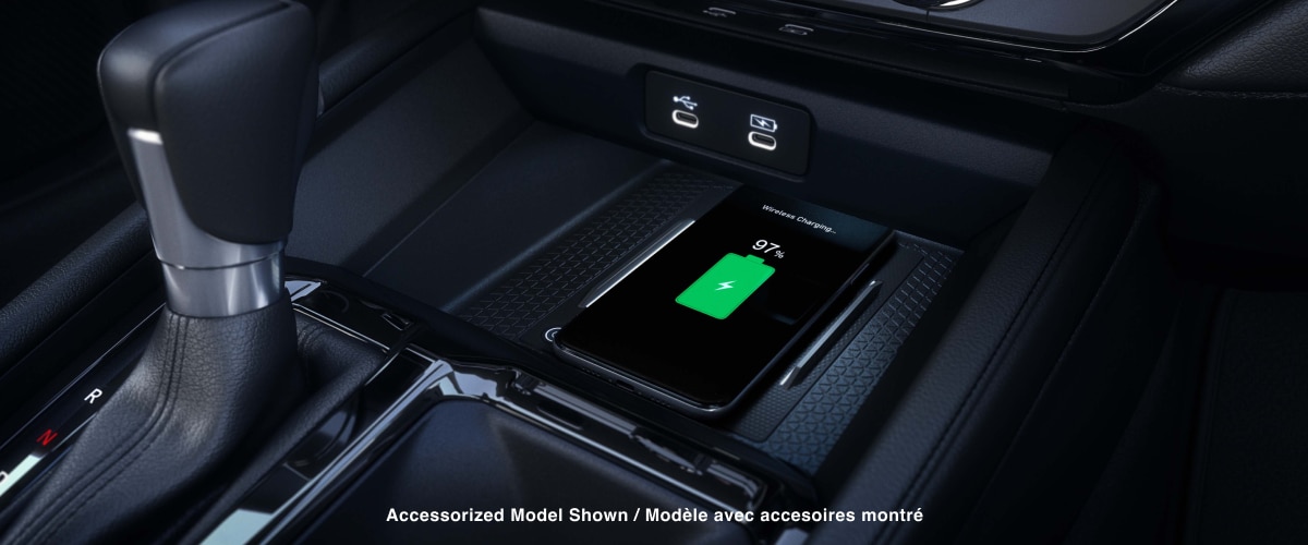 Closeup view of a compatible smartphone charging wirelessly on the charging pad in front of the gear shifter.