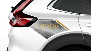 Gros plan de l’aile noire d’un CR-V HPD blanc sur fond blanc. La décalcomanie de lettres grises et or indique : HPD.