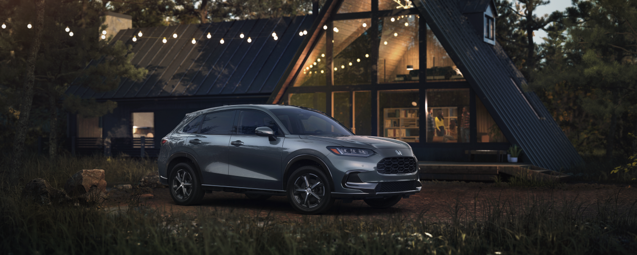 3/4 front side view of grey HR-V park in front of an A-frame cottage. 