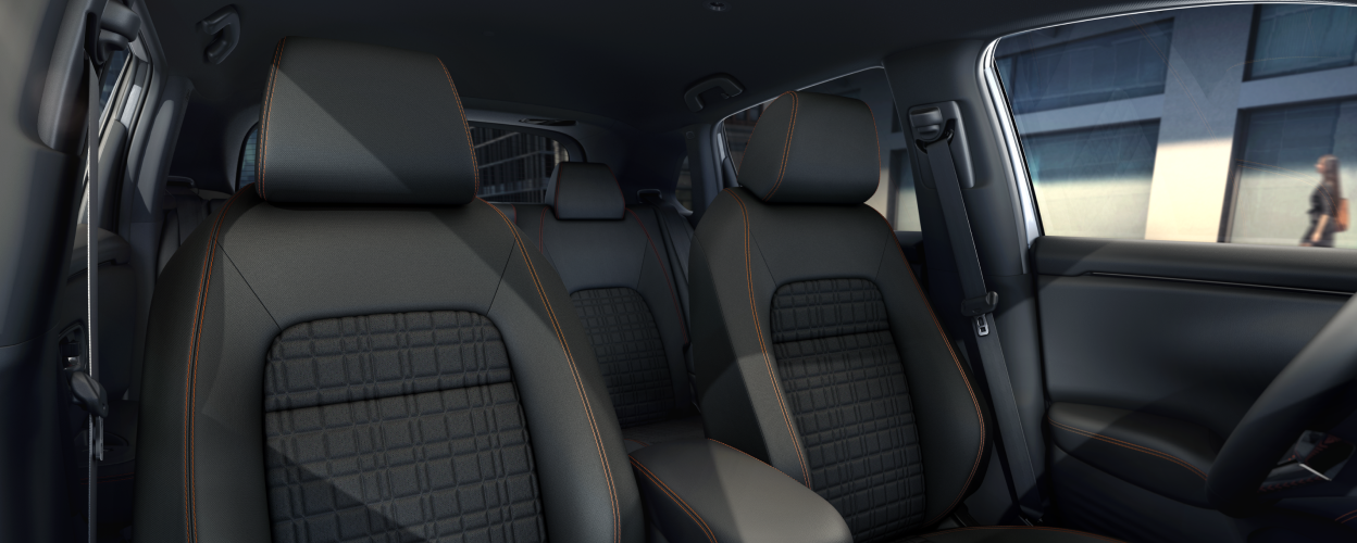 Wide view of front black front seats with orange stitching. 