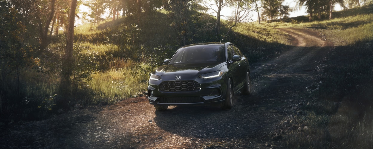3/4 front view of black HR-V driving toward camera on dirt country road.