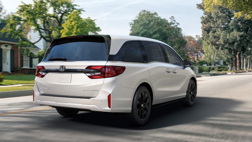 Vue latérale d’une Odyssey blanche stationnée au bord d’un lac.