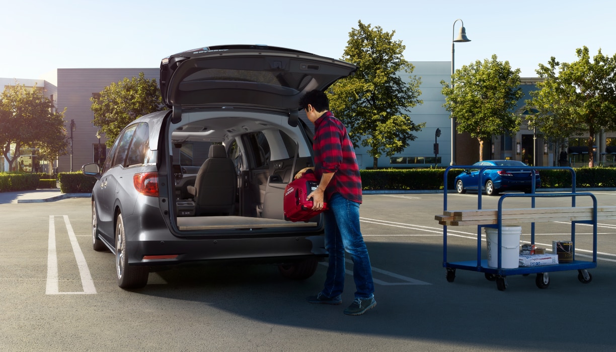 Man loading up Odyssey trunk in empty parking lot.