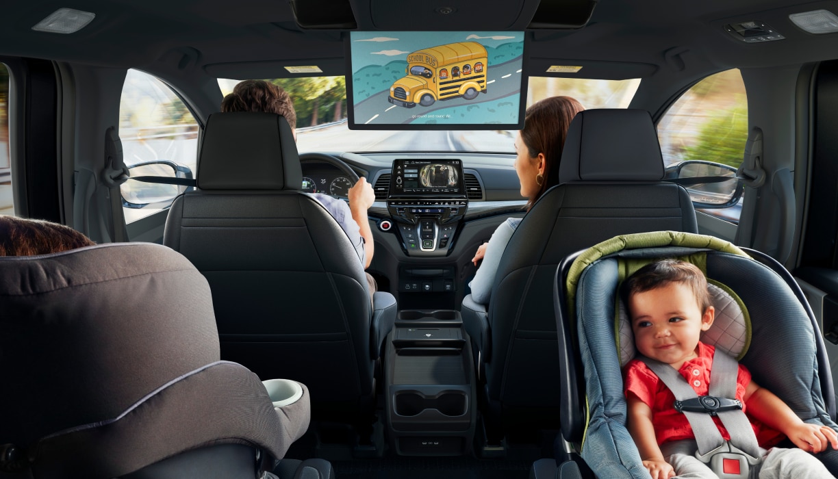 Habitacle de l’Odyssey. Père au volant; mère dans le siège passager avant; enfant dans son siège d’auto.