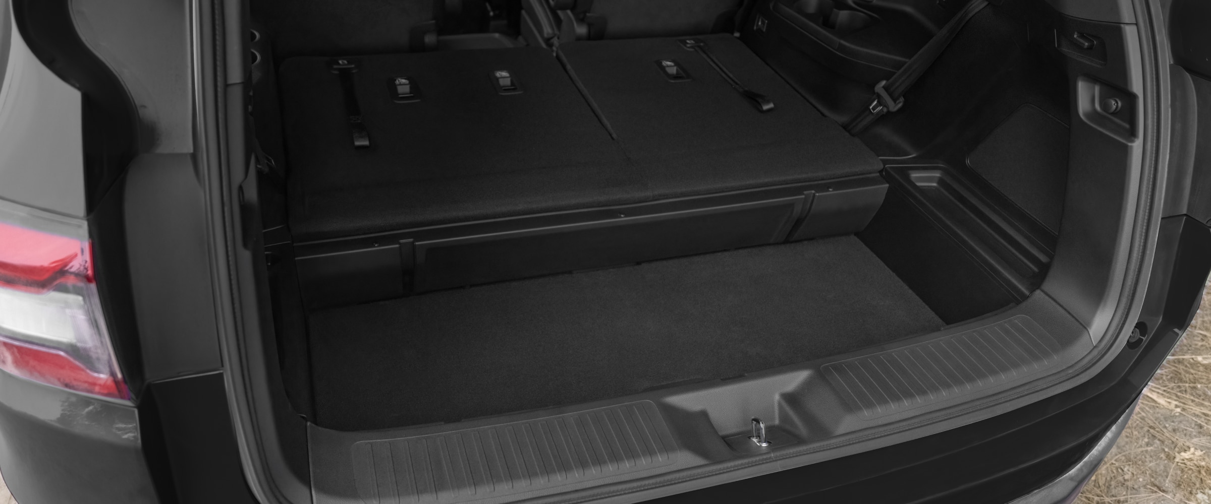 View of open tailgate showcasing the on-demand, in-trunk storage, with the third row of seats folded down.