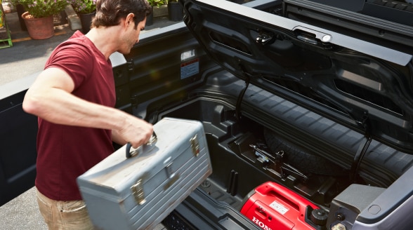 Man loading toolbox into lockable In-Bed Trunk.