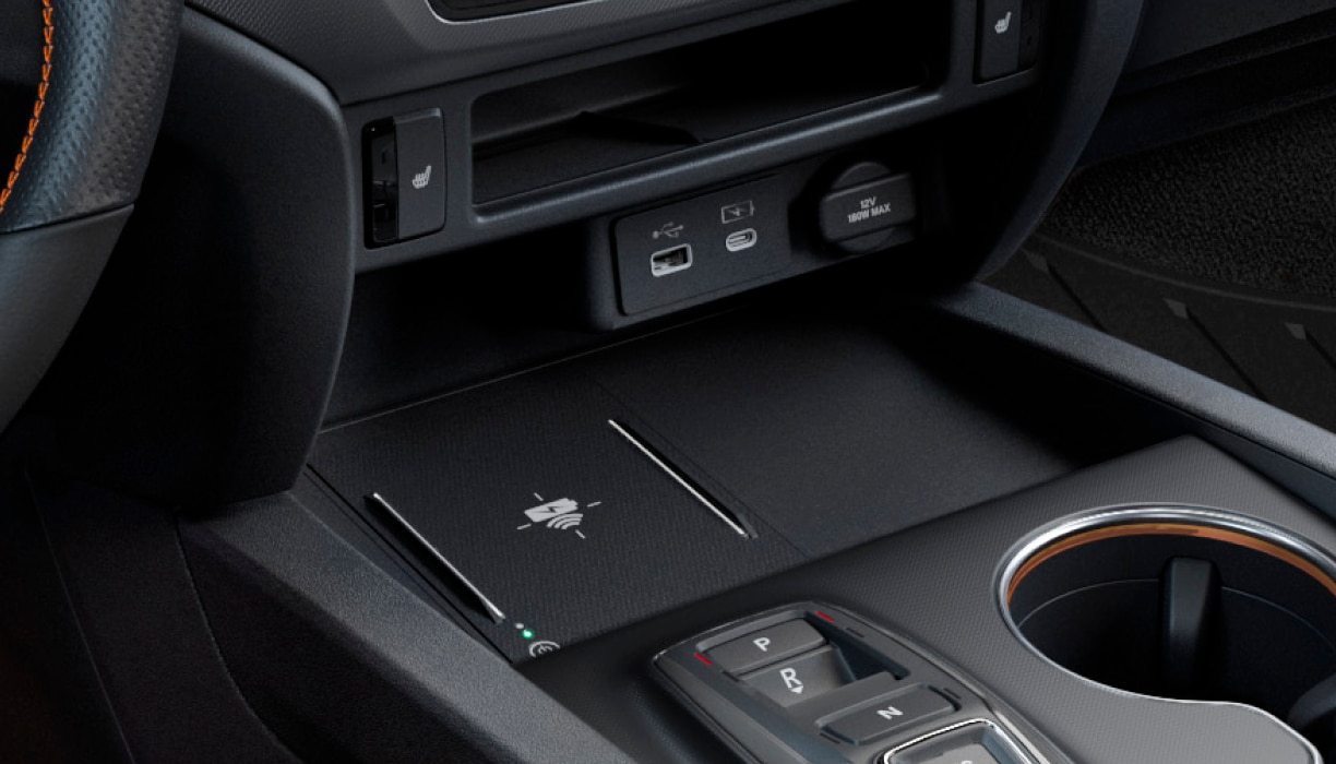 Gros plan sur les ports de recharge USB et le socle de recharge sans fil dans la console centrale.