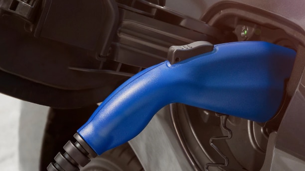 Gros plan d’une fiche de recharge bleue dans la prise d’un véhicule électrique. 