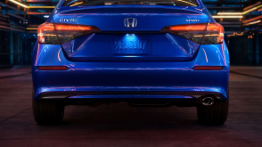 Rear view of a parked blue Civic Sedan in a dark warehouse-like space.