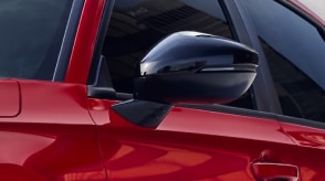 Closeup of a black door mirror on a red Civic Sedan.