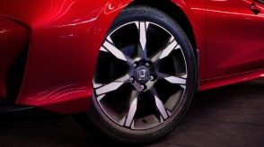 Close up of the front wheel on a parked red Civic Sedan.