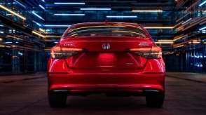 Rear view of a parked red Civic Sedan in a dark warehouse-like space.