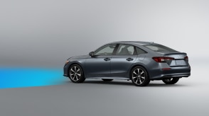 3/4 side rear view of grey Civic Sedan on white space. Blue sensor waves emit from the front. 