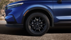 Sideview of the front of a blue CR-V, highlighting its black aluminum-alloy wheel.