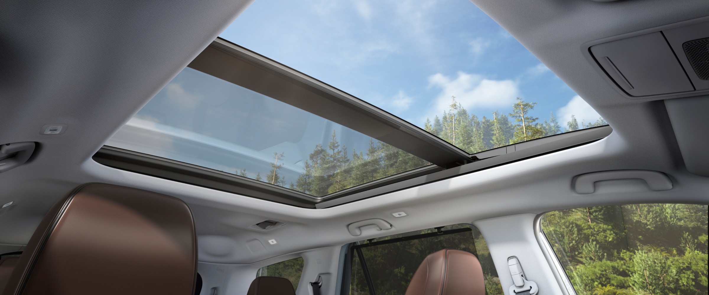 Vue prise de l’intérieur du Pilot, pointant vers le ciel bleu et les arbres à travers le toit ouvrant panoramique.