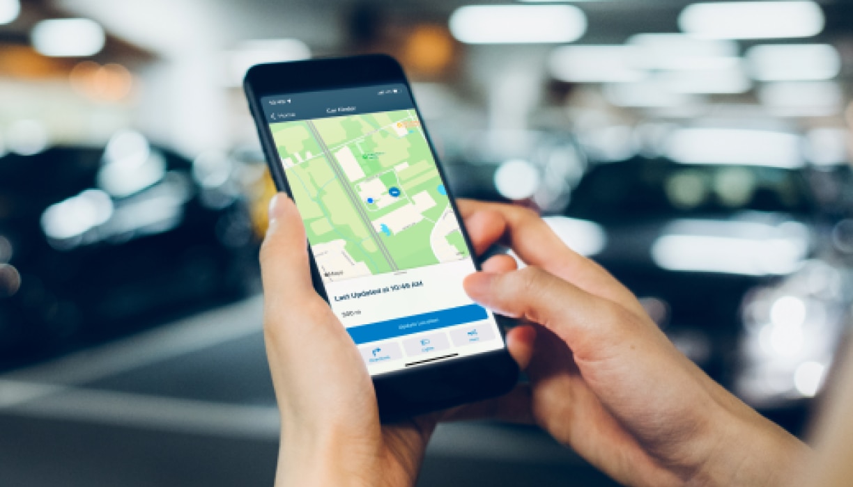 Gros plan de mains tenant un téléphone avec l’application HondaLink ouverte.