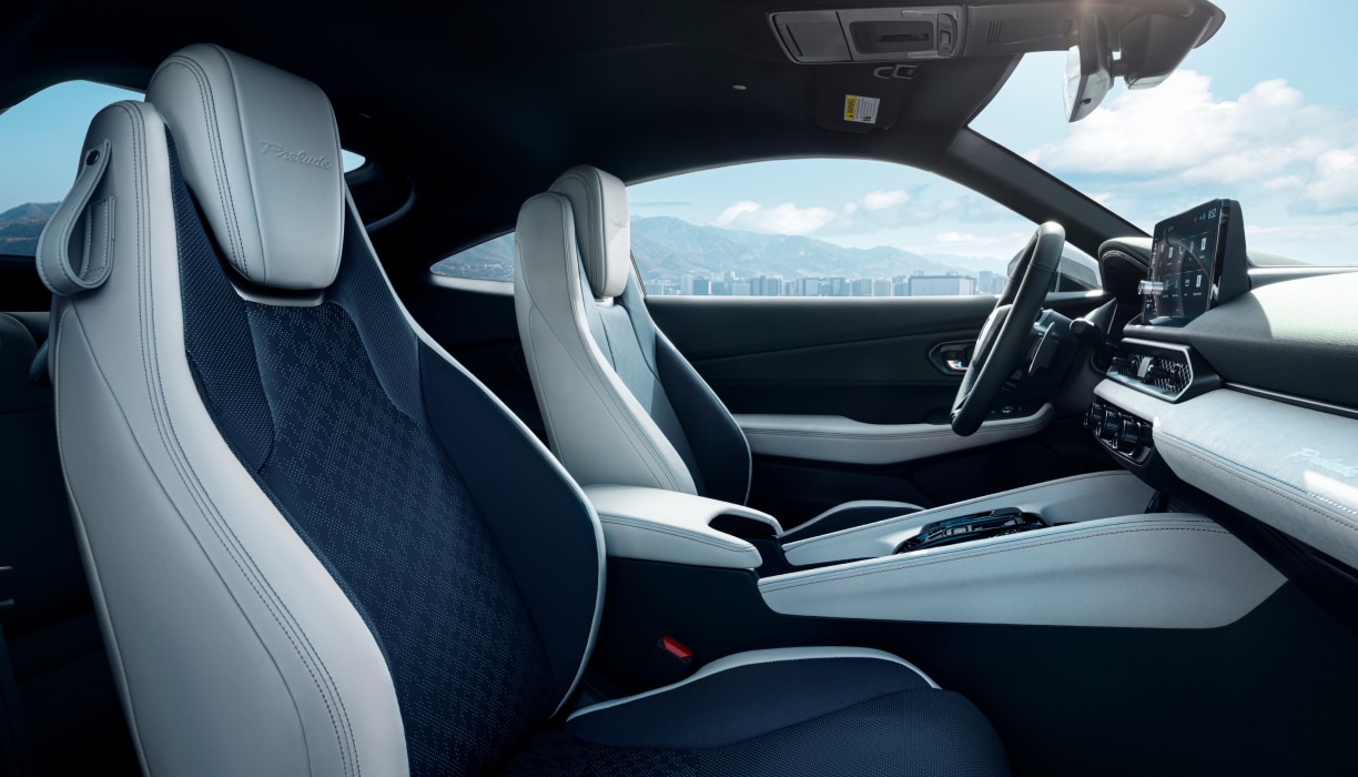 Passenger's side view of Prelude's black and white front row seats, steering wheel, and dashboard.